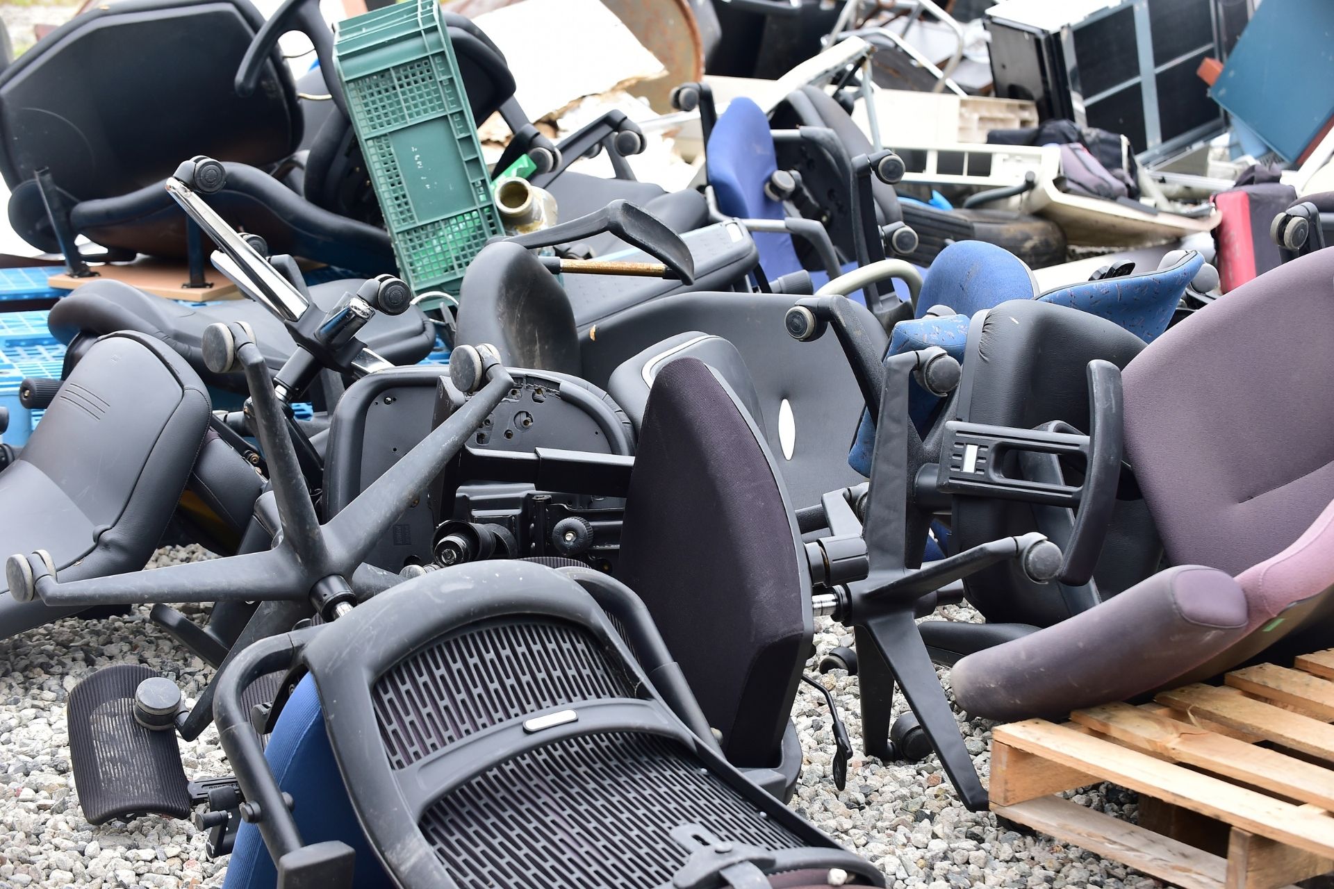 Cluttered pile of discarded office chairs with debris and a green plastic crate scattered around